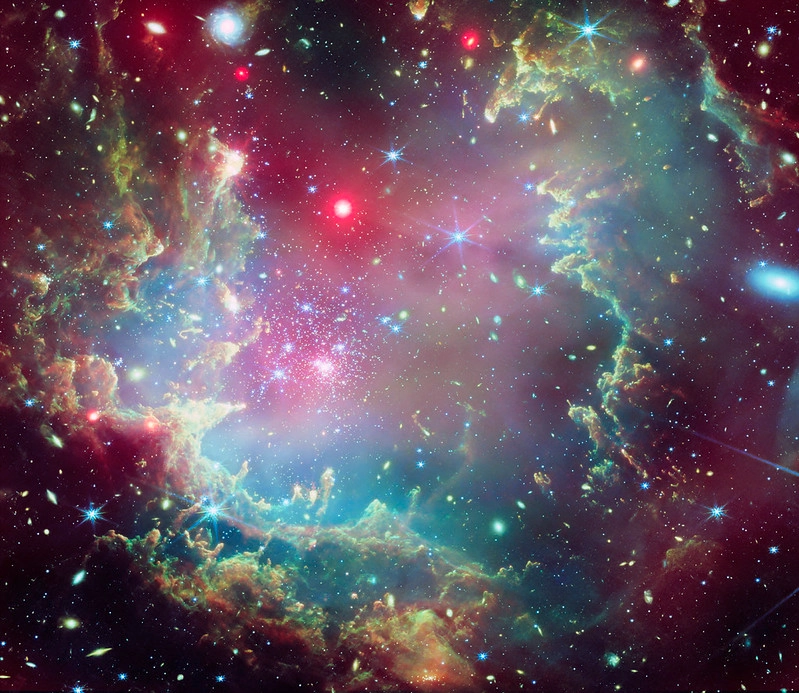 Composite of Chandra X-ray and Webb infrared data: star cluster NGC 602 in the Small Magellanic Cloud, showing a wreath-like ring of gas and dust.